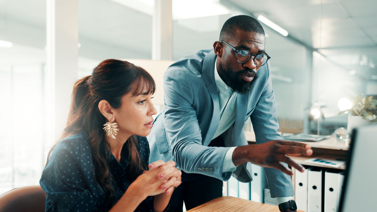 Two financial executives looking at a computer in an office together